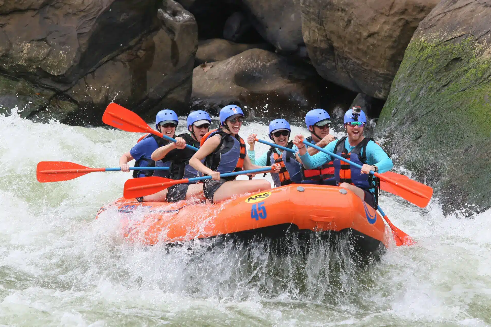 A group of people rafting together as a team in whitewater rapids, demonstrating recreational team building