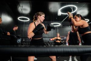 Boxing studio class in Boise. Woman in boxing gloves training with partner. Private fitness studio workout.