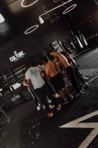 Boxing class huddles in a private studio at Assemble Boise, preparing for their boxing workout with punching bags.