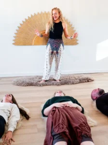 Assemble Boise breathwork session: woman guiding a group lying down, relaxing during wellness activity.