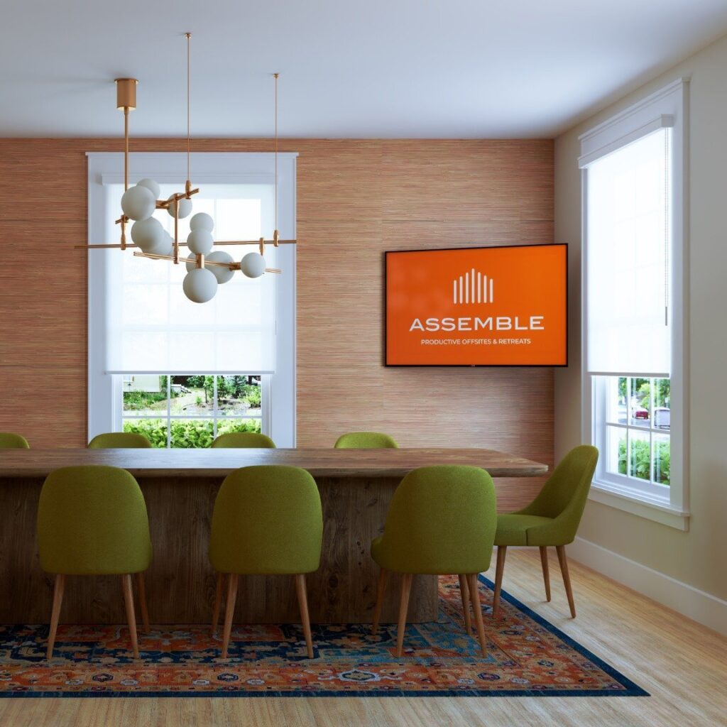 Facilitation services meeting room in Boise with conference table, chairs, and Assemble logo on screen. Productive offsite retreats.