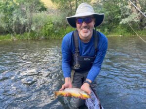Happy fly fisherman in Boise river holding a trout. Flyfishing image gallery assemble Boise.
