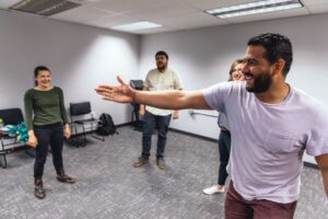 Enthusiastic people enjoying an improv class in Boise, Assemblae. Group acting workshop, creative fun, acting exercises.
