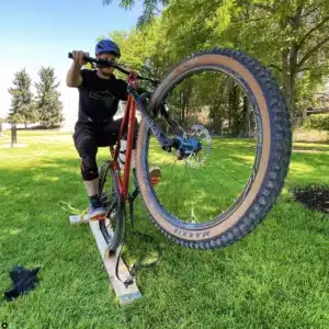 Mountain biker at a clinic balancing on a beam, showcasing skills. Boise mountain biking training session.