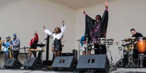 Assemble Boise music experience: Live band performs with singers, musicians, and drums on stage. Boise music event.