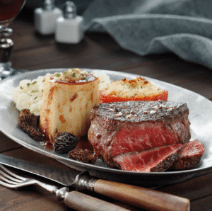 Private Dining Boise: Close-up of a delicious plated meal featuring steak, side dishes, and morel mushrooms at Four Assemble.