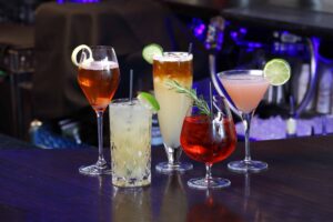 Private Dining Boise: Selection of cocktails on a bar, featuring colorful drinks with citrus and rosemary garnishes.