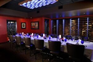 Private dining room in Boise with long table set for a special event, wine rack, and modern lighting.