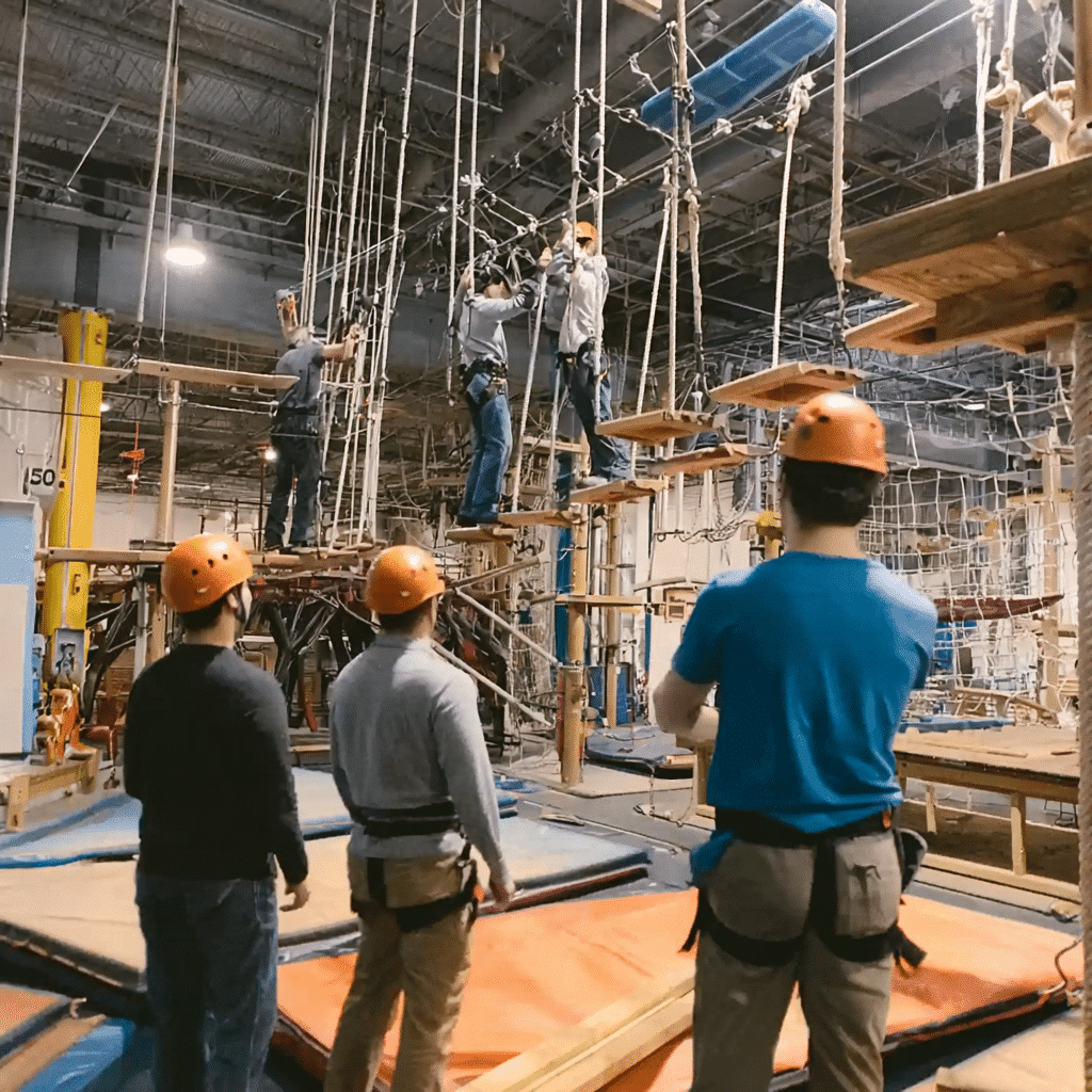 Ropes Course in Boise: People navigating a challenging indoor ropes course with safety gear. Adventure and team building activity.