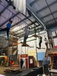 Assemble Boise ropes course with people navigating high obstacles. Indoor adventure and recreational activities.