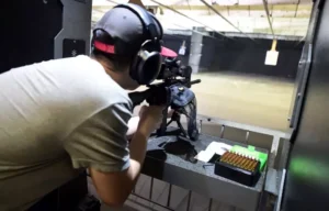 Shooting range: Man aiming rifle with scope at target. Boise indoor gun range for firearms practice and sport shooting.