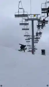 Snowboarder performing trick on snowy slope with ski lift in background. Boise snowsports scenic, action shot.