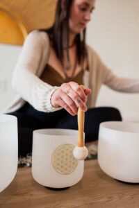 Sound Healing session with crystal bowls for meditation and relaxation in Boise. Woman playing sound bowls.