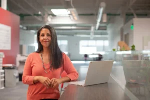 Speakers Bureau: Professional woman with laptop in Boise office. Assemble Speakers for your next event.