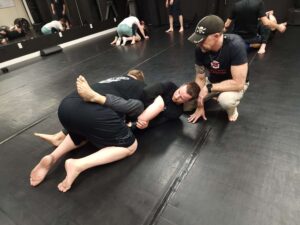 Tactical training session: instructor guides students in ground fighting techniques at Assemble Boise. Martial arts instruction.