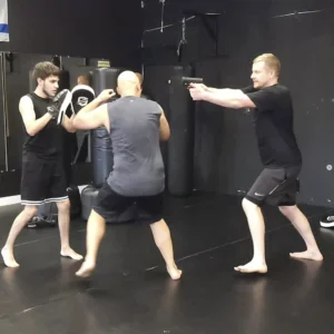 Tactical Training: Man with gun training self defense with sparring partner and instructor at Assemble Boise. Firearm safety.