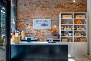 House of Wine Boise interior with brick wall, wine poster, retail shelves, and reception counter for wine education.