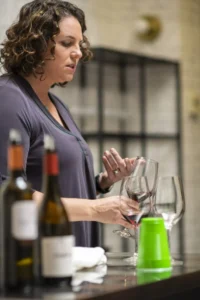 Wine education class in Boise with wine bottles and glasses. Woman explaining wine tasting. Assemble Boise wine event.