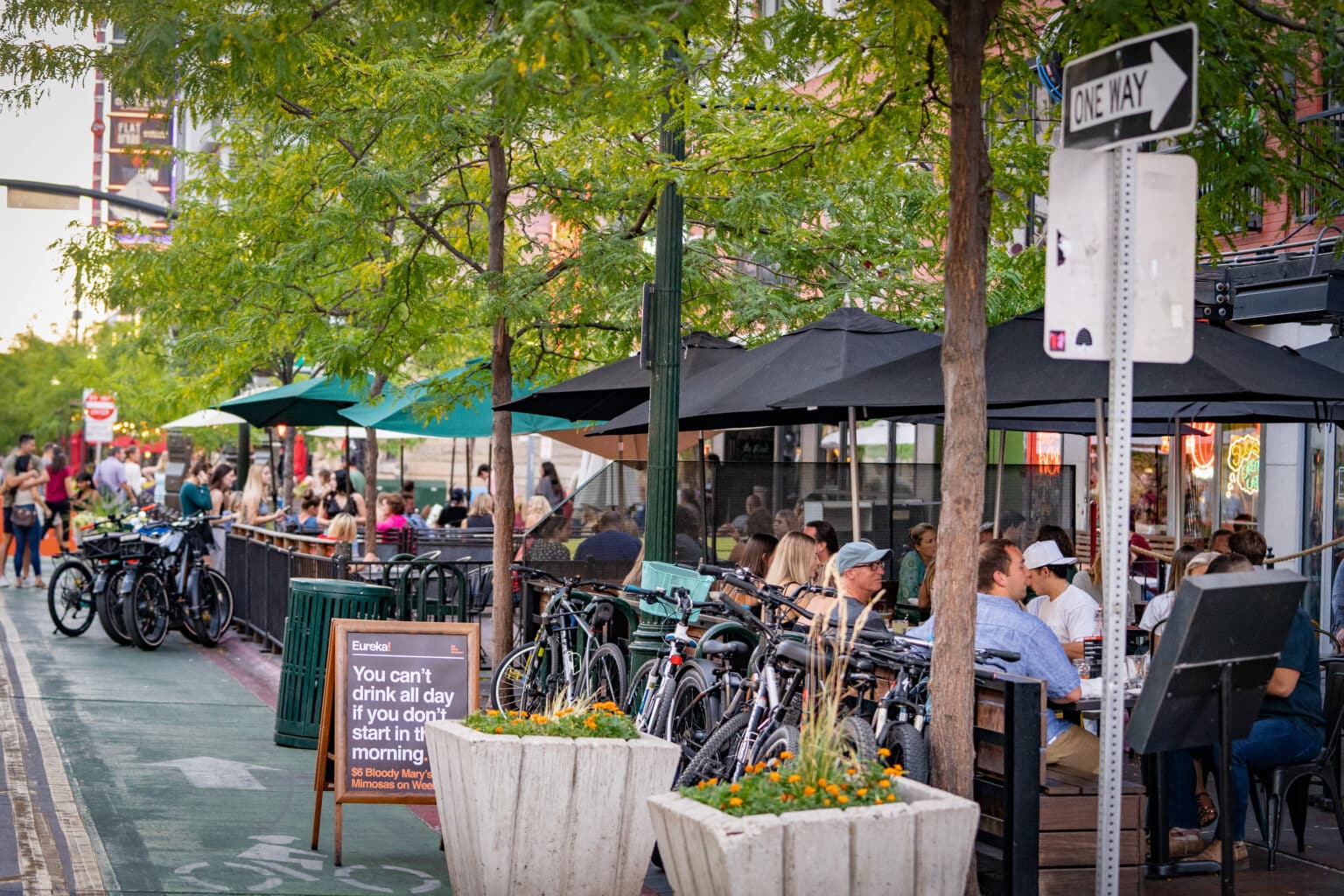 Where to stay in Boise, ID — busy downtown sidewalk with outdoor restaurant patios, umbrellas, bikes, and diners.