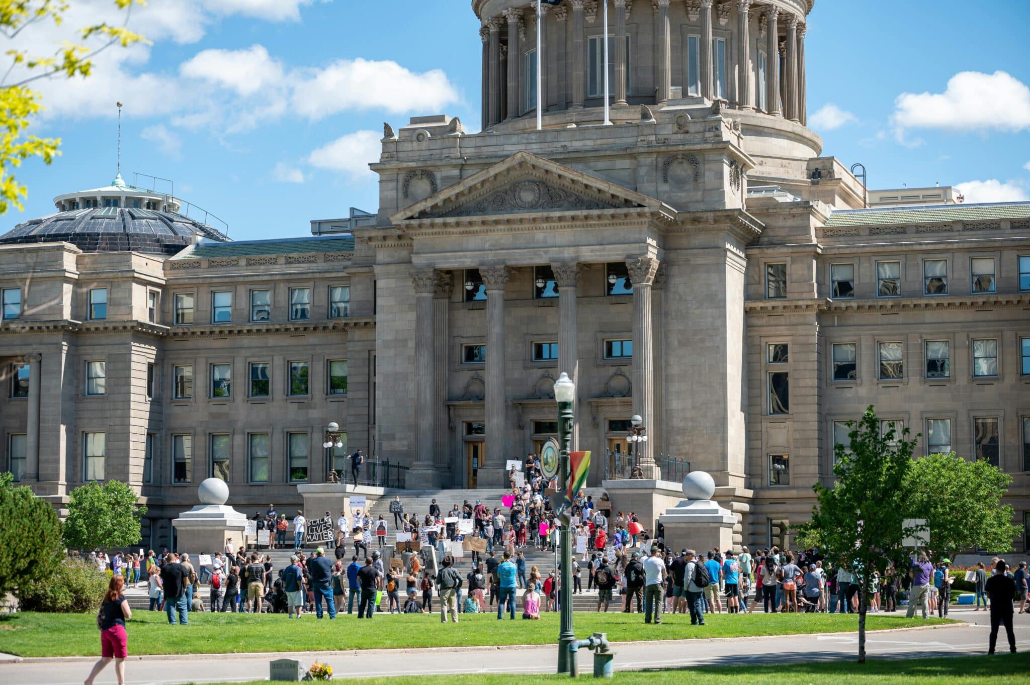Crowd gathered in front of a large domed building near Boise State University on a sunny day in Boise.